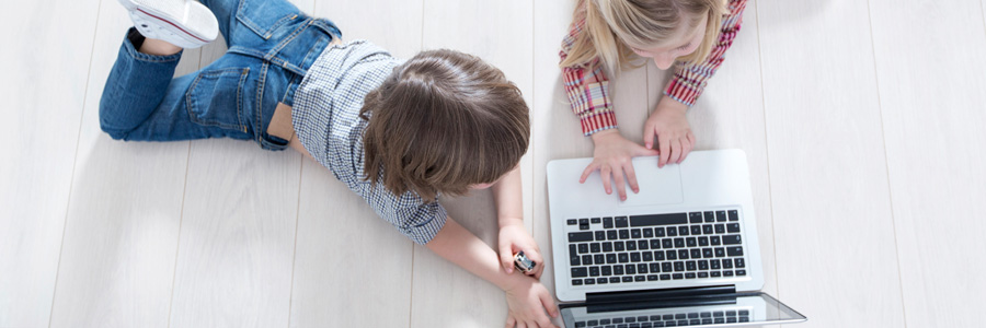 Kinder auf dem Boden liegend vor Laptop
