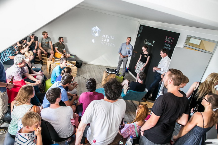 Junge Menschen sitzen auf Kisten im Media Lab zusammen Junge Menschen sitzen auf Kisten im Media Lab zusammen